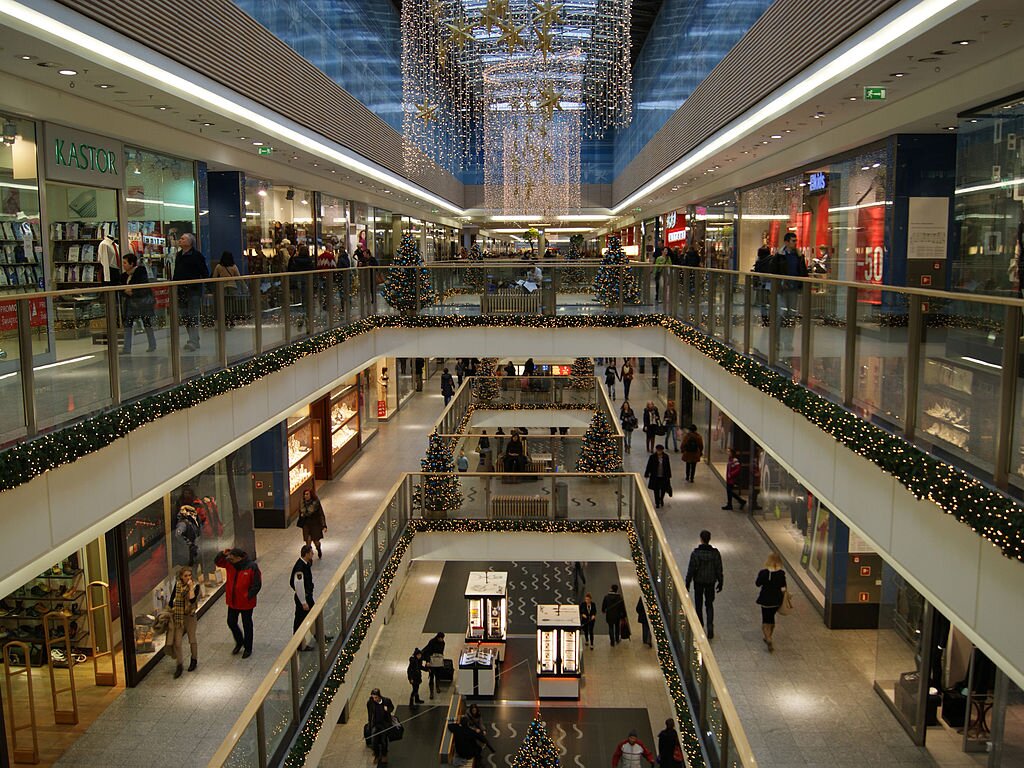 Fotografia barwna przedstawiająca wnętrze krakowskiego centrum handlowego, udekorowanego bożonarodzeniowymi lampkami.