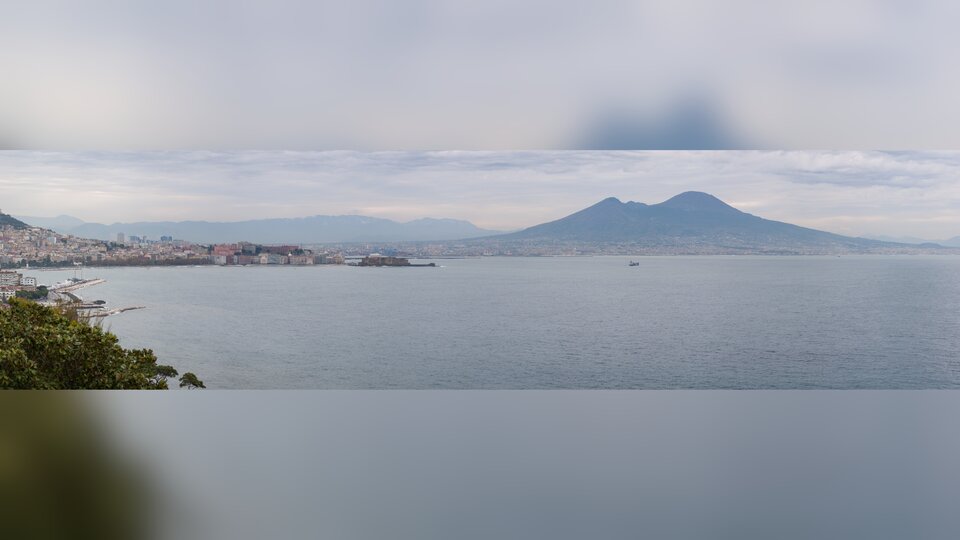 Zdjęcie przedstawia dużą, morską zatokę. W oddali znajduje się ląd i wysoka góra.