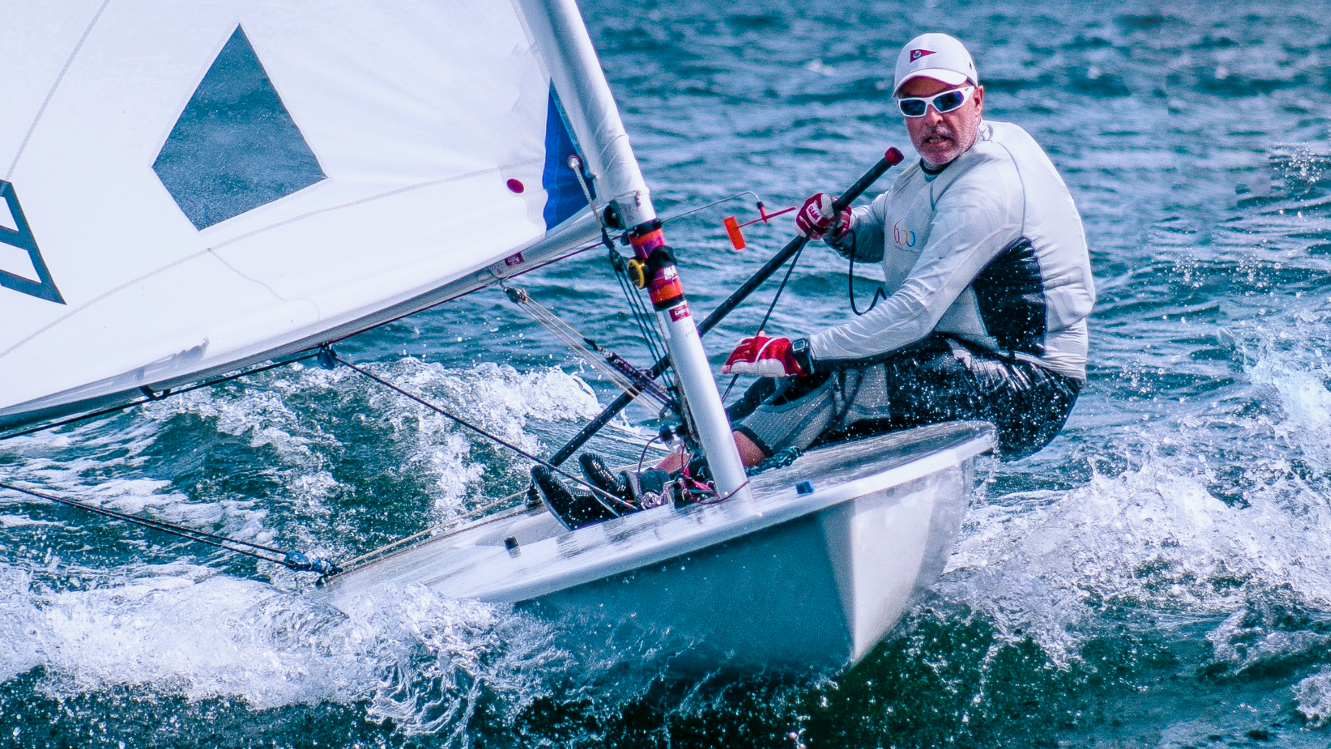 Zdjęcie przedstawia sportowca płynącego żaglówką.