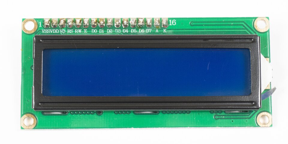Zdjęcie przedstawia zieloną płytkę elektroniczną wraz z ekranem wyświetlacza LCD. Na górnej krawędzi znajduje się 16 złączy. Są oznaczone symbolami literowymi i cyframi. Są to kolejno: VSS, VDD, V0, RS, RW, E, D0, D1, D2, D3, D4, D5, D6, D7, A oraz K.