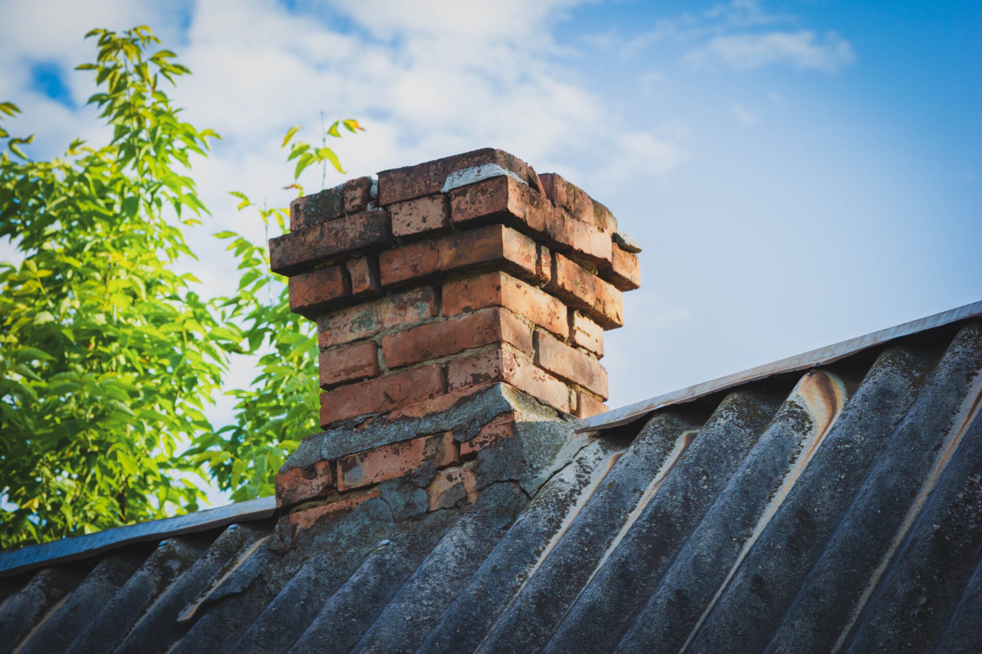 Zdjęcie przedstawia podniszczony ceglany komin.