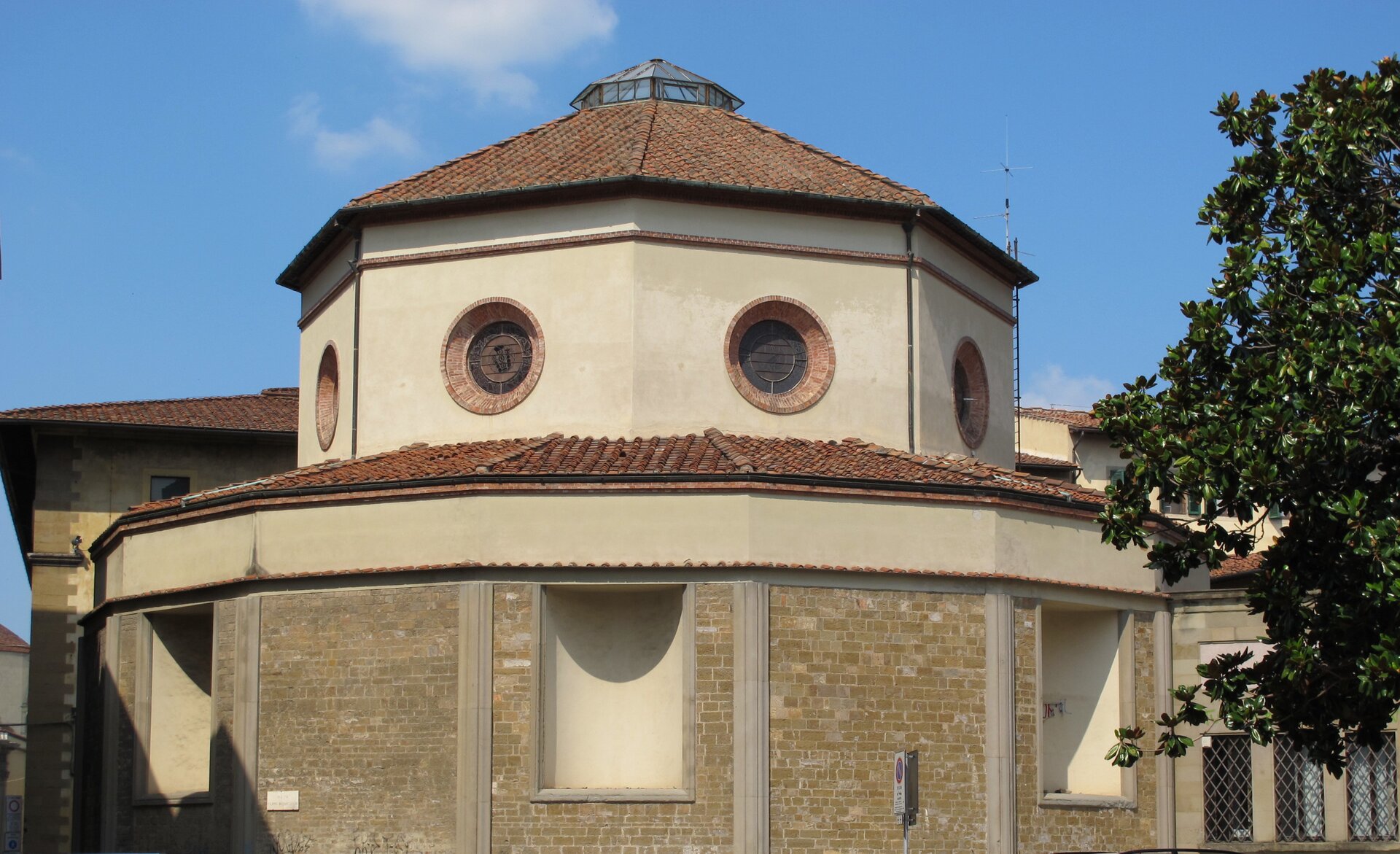 Na zdjęciu znajduje się fragment klasztoru. Jest to niski budynek o ciemnoczerwonym dachu zbudowany na bazie wielokąta foremnego. W swojej górnej części posiada okrągłe okna.