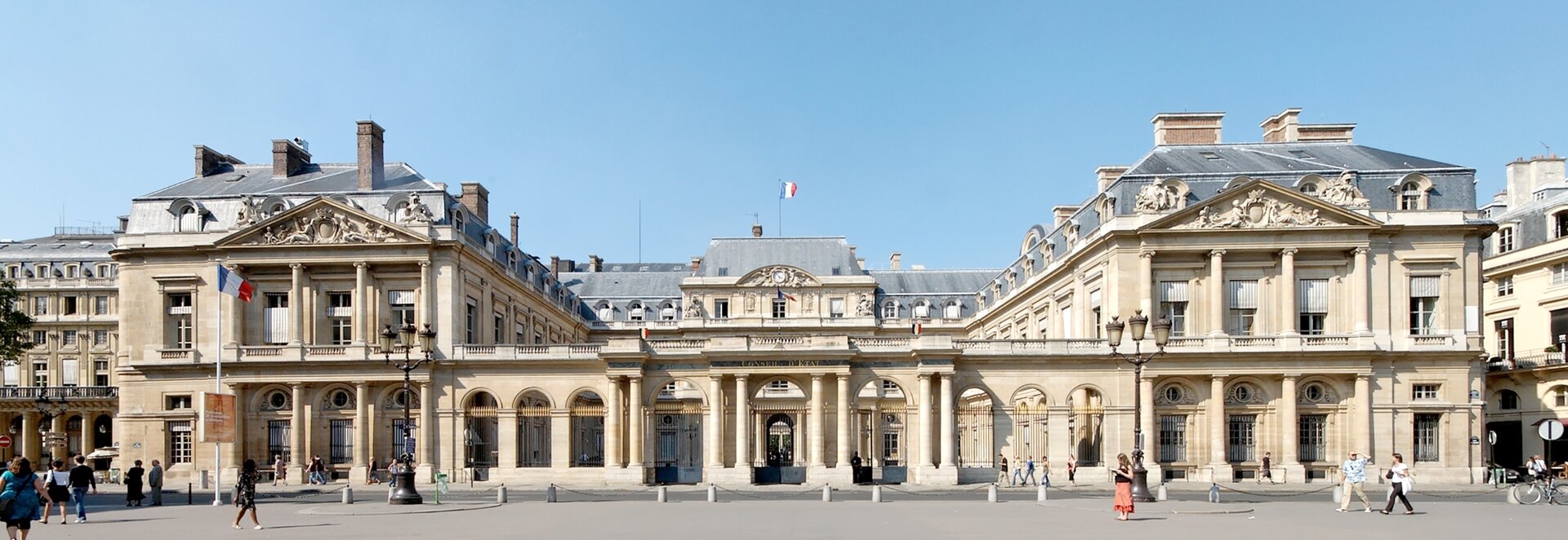 Zdjęcie przedstawia duży, neoklasycystyczny, dwuskrzydłowy pałac. Fronton pałacu wsparty jest na ośmiu kolumnach. Przed pałacem znajduje się wyłożony kostką plac.