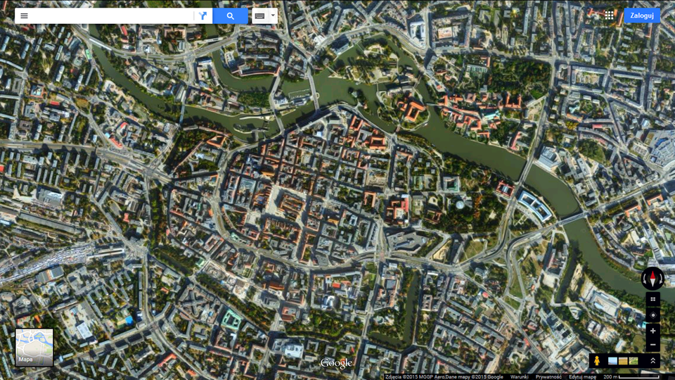 Fotografia druga przedstawia lotnicze zdjęcie centrum Wrocławia w Google Maps. Dobrze widoczny układ ulic i zabudowy. Widać czerwone i szare dachy. Z prawego dolnego rogu do lewego górnego rogu wije się rzeka Odra. Można dostrzec również mosty i drzewa.