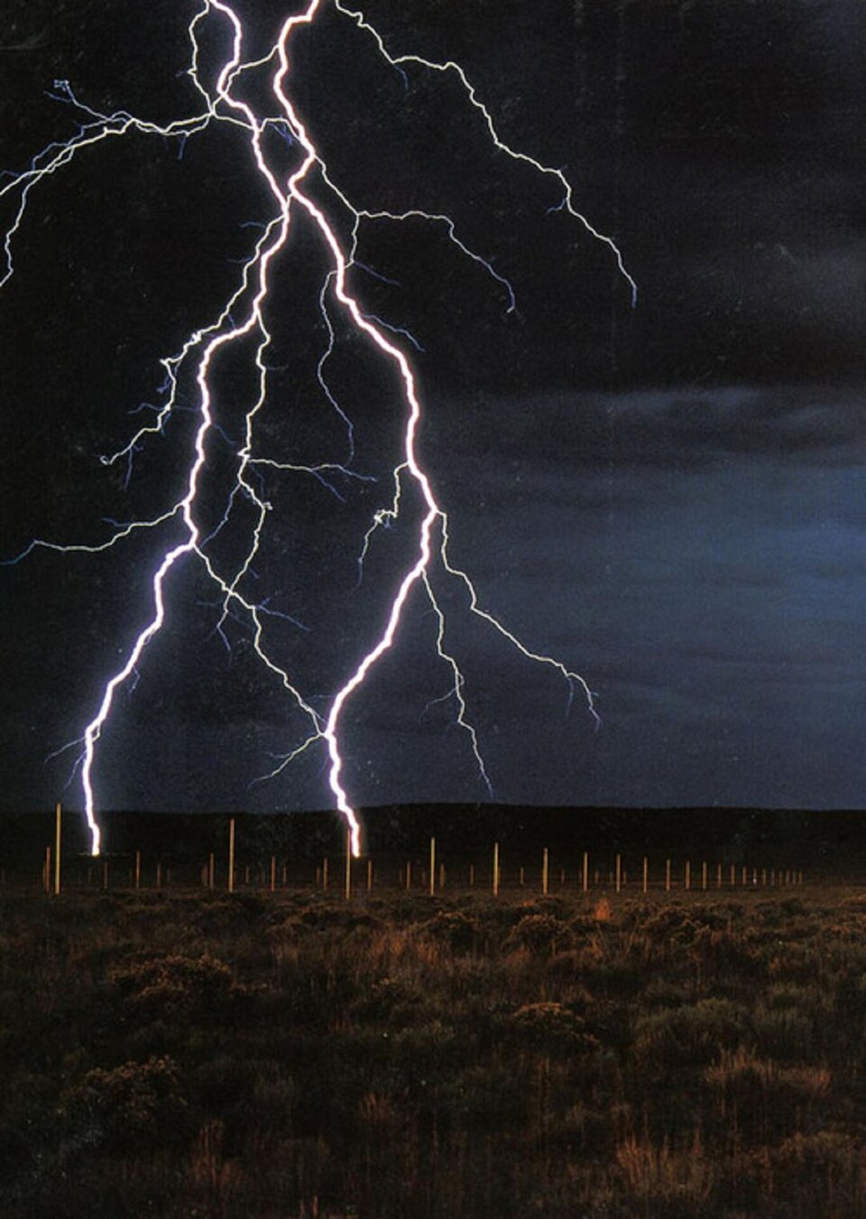 Zdjęcie przedstawia ciekawy przykład land art „Pole błyskawic” Waltera de Marii (1977). Na pustyni artysta umieścił 400 metalowych drągów, które przyciągają pioruny.