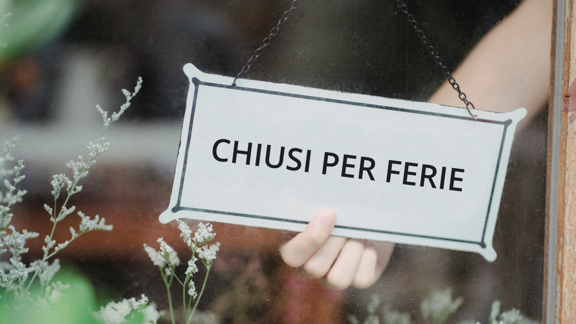 Zdjęcie przedstawia witrynę na której znajduje się tabliczka z napisem: "Chiusi per ferie".