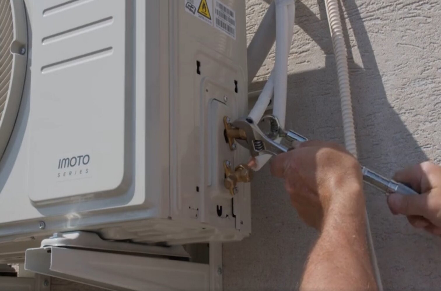 Zdjęcie przedstawia podłączenie rur chłodniczych do jednostki zewnętrznej klimatyzatora. Pracownik montuje rury za pomocą klucza.
Opisy prezentowanych na grafikach obiektów są załączone w treści.