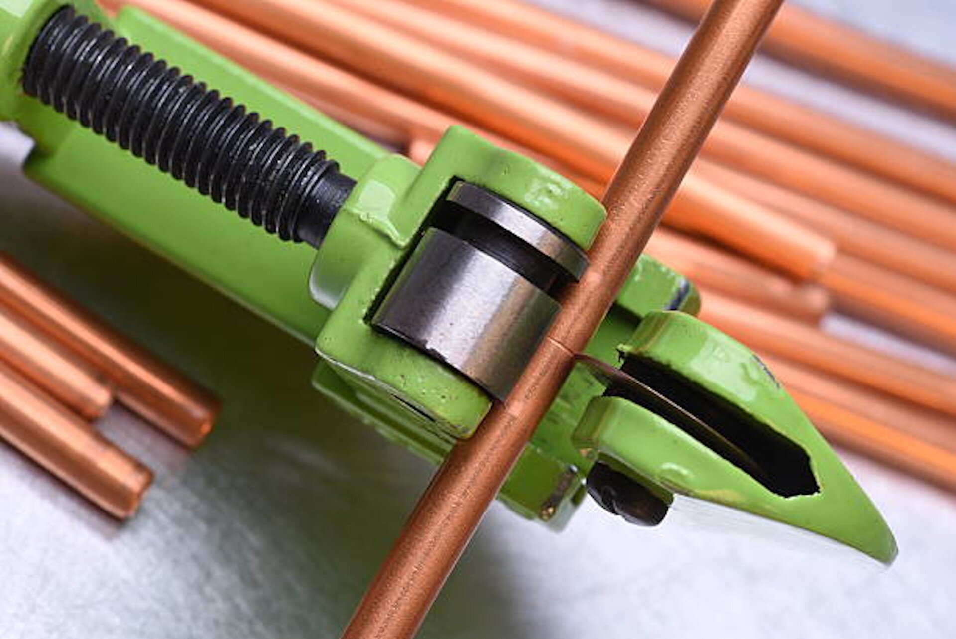 Na zdjęciu prezentowane jest narzędzie do precyzyjnego cięcia rurek. Jego korpus wykonany jest z żeliwa, a w górnej części znajduje się niewielka tarcza tnąca oraz element w kształcie walca. Pomiędzy nimi widoczna jest szczelina, służąca do umieszczenia rurki. Dzięki temu narzędzie umożliwia dokładne, skuteczne i precyzyjne cięcie rurek.