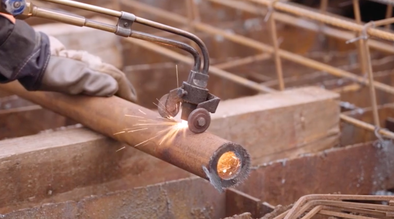 Na zdjęciu widoczne jest cięcie rury palnikiem gazowym. Palnik to dwie zakrzywione rurki, na końcach których widoczne są niewielkie kółeczka służące do stabilizacji palnika opartego o przecinaną rurę. Poniżej ilustracji znajduje się przycisk do odtworzenia nagrania.