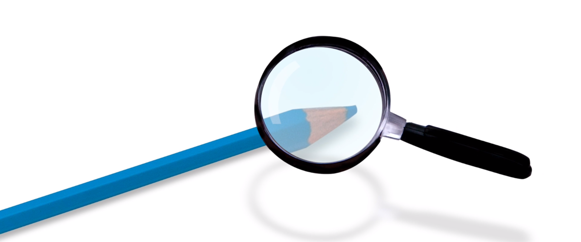 Na rysunku znajduje się lupa i widziany przez nią powiększony obraz ołówka.