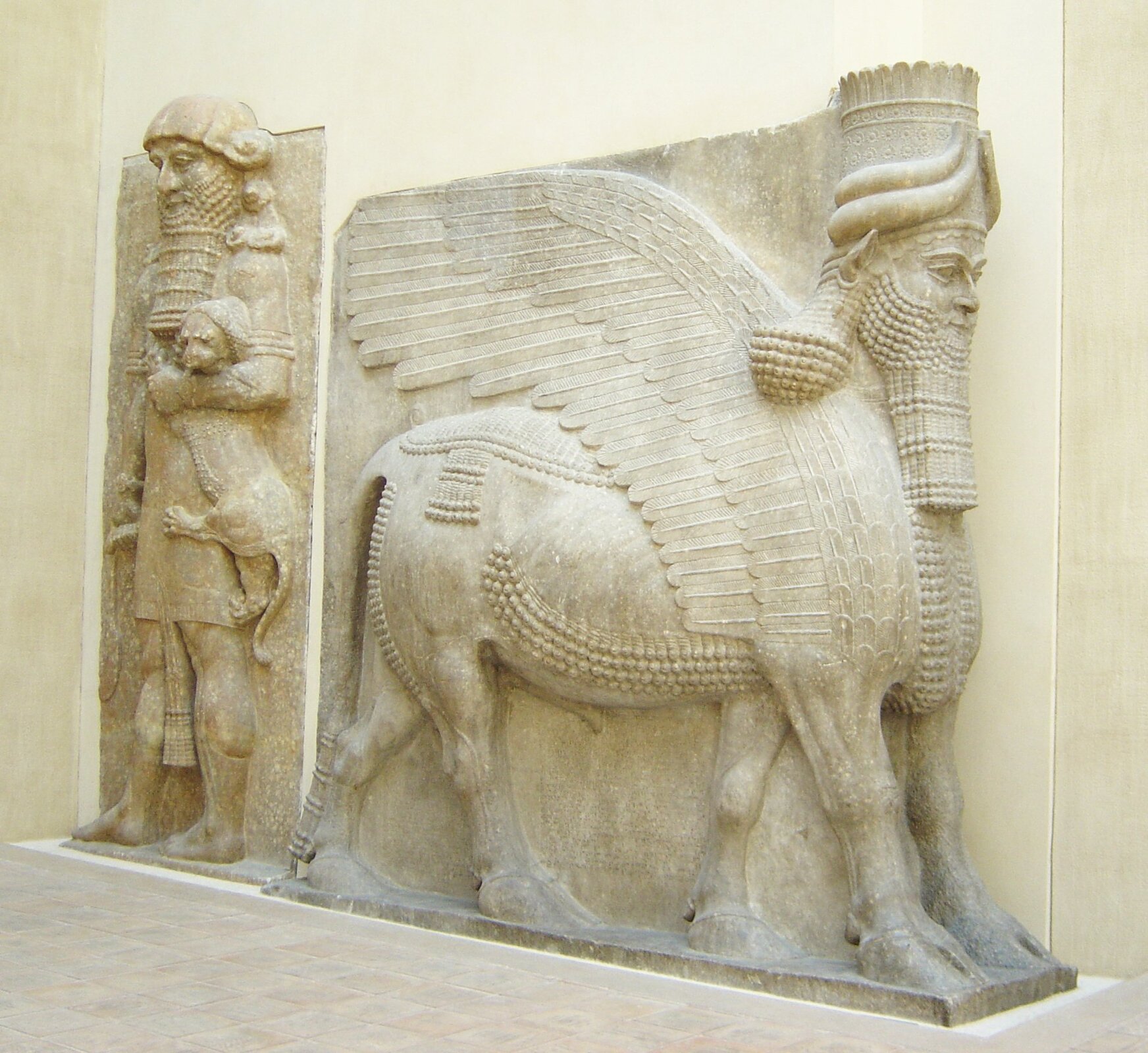 Ilustracja przedstawia dwie płaskorzeźby z bramy pałacu Sargona II. Pierwsza ukazuje lamassu, czyli skrzydlatego byka z ludzką głową uosabiającego ducha opiekuńczego. Jego ciało jest masywne, głowa sztywna. Posiada pięć nóg. Kolejna płaskorzeźba ukazuje Gilgamesza, poskramiającego lwa. Smukła postać z długą brodą w lewym ręki trzyma za głowę niewielkiego lwa. Głowa i tułów Gilgamesza przedstawione są centralnie, a nogi z boku. Ubrany jest w tunikę. 