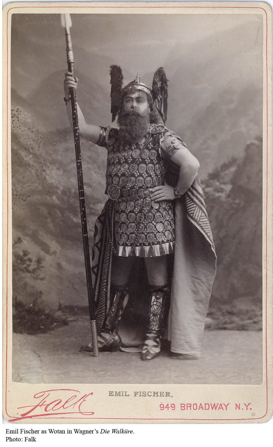 Ilustracja przedstawia Emila Fischera jako Wotana, podczas premiery „Złota Renu” w Nowym Jorku w 1889 r. Mężczyzna stoi w prawej ręce trzyma drewnianą strzałę, która jest od niego dłuższa. Lewą rękę podpiera się o biodro. Ubrany jest w zbroję, ma metalowe zakrycie głowy. Twarz ma niewyraźną, ale widać wąsa i długą brodę.