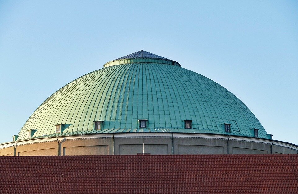 Zdjęcie przedstawia budynek z dachem kopulastym. Dach jest koloru morskiego. 