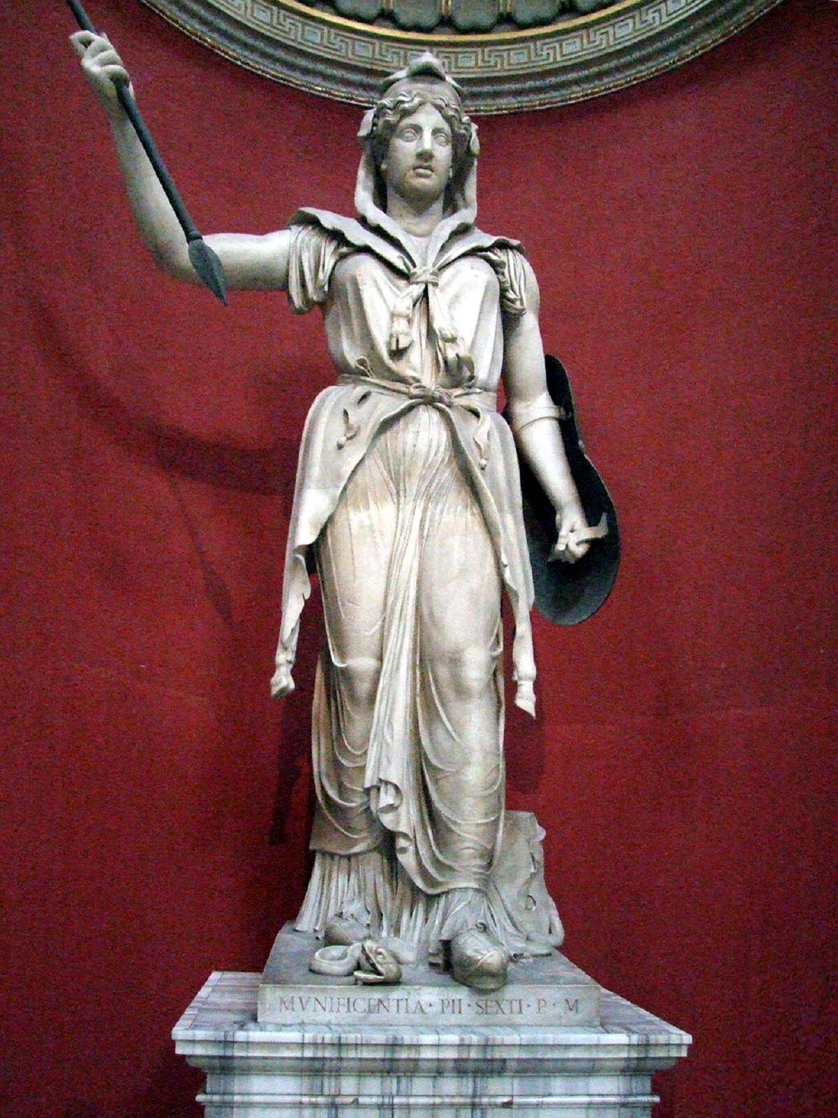 Rzeźba nieznanego autora przedstawia postać Junony -bogini rzymskiej, która została przedstawiona jako szczupła kobieta w średnim wieku, ubrana w welon zakrywający jej włosy, oraz długą szatę zakrywającą jej ciało. Junona jedną rękę ma uniesioną do góry i trzyma w niej włócznię, do drugiej ręki przymocowana została tarcza. Rzeźba została wykonana z jasnego kamienia, stoi na cokole, na którym widoczne są łacińskie inskrypcje. Figura Junony została sfotografowana na tle czerwonej ściany. 