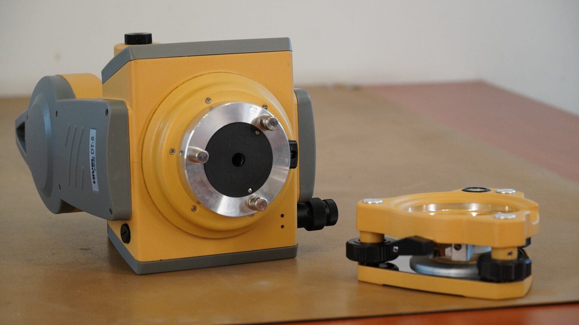 Na zdjęciu przedstawiono teodolit po zdemontowaniu korpusu alidady. Na prawo od urządzenia znajduje się zdemontowana podstawa.