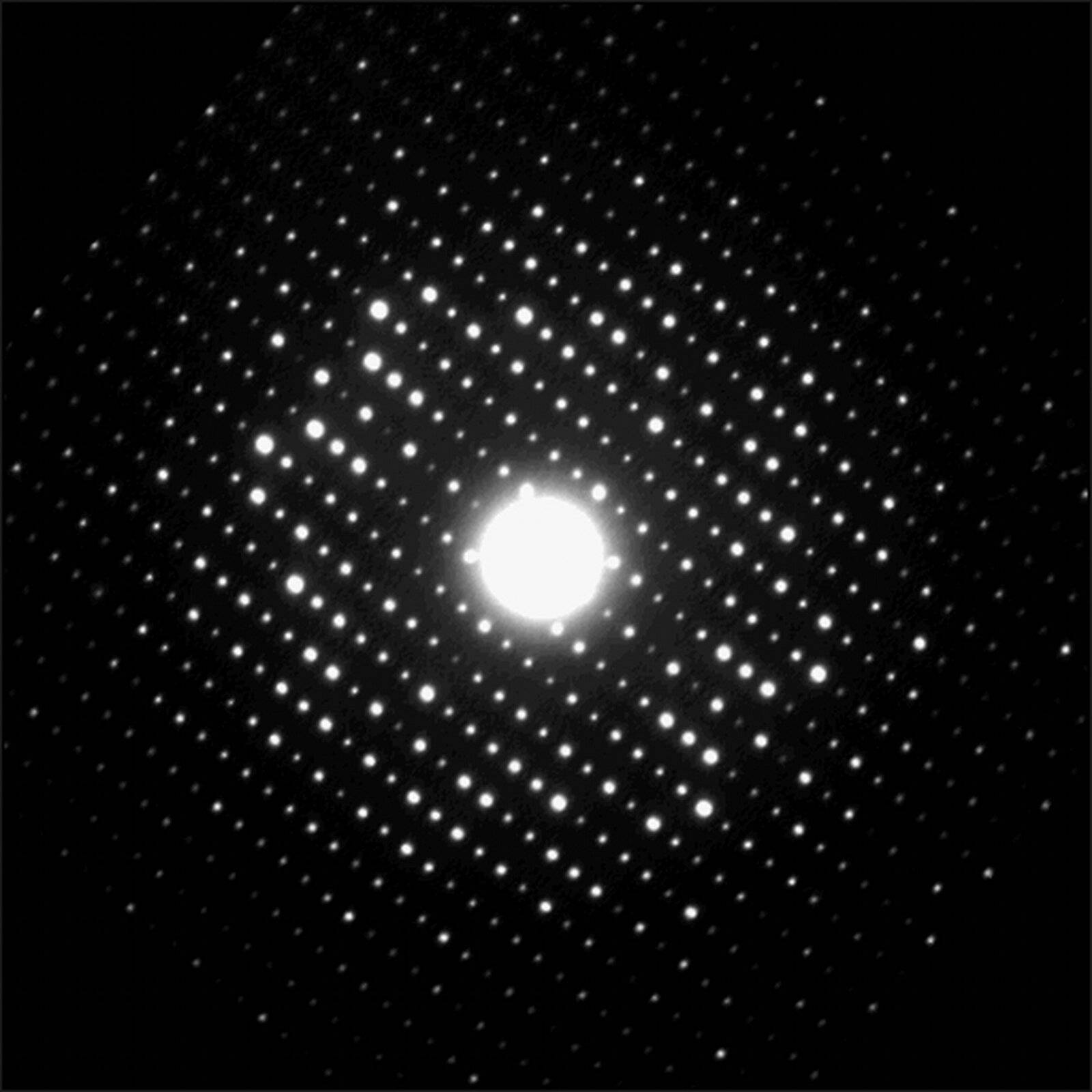 Zdjęcie przedstawia obraz dyfrakcyjny elektronów na krysztale tlenku tantalu. Na czarnym tle widać układ białych kółek wokół jednego dużego białego koła. Obraz ma wyjątkowo symetryczną strukturę.