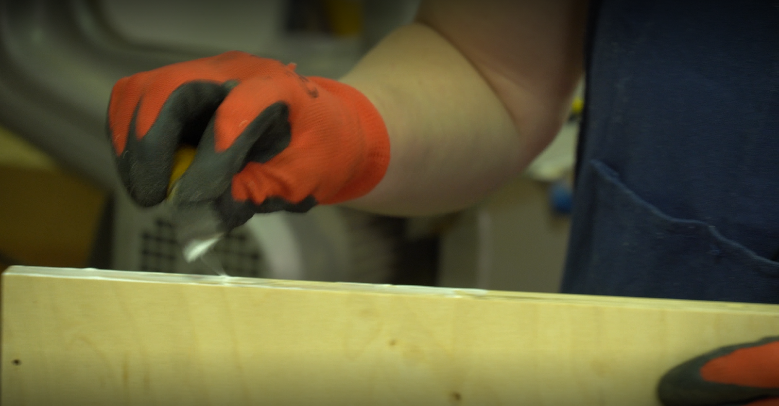 Zdjęcie pokazuje, jak tapicer nakłada warstwę kleju na brzeg elementu skrzyni.