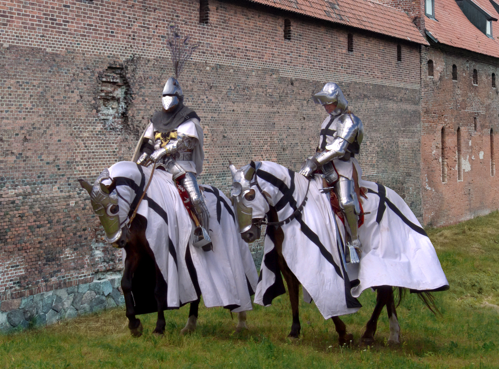 Ilustracja przedstawia dwóch rycerzy zakonu krzyżackiego. Obydwaj siedzą na koniach, ubrani są w zbroje, które pokrywają całe ich ciała. Konie okryte są tkaniną, na której Znajduje się symbol zakonu, czyli czarny krzyż na białym tle. Ponadto symbol ten umieszczony jest na wierzchniej odzieży, którą rycerze mają założoną na zbrojach. Rycerze mają na głowie hełmy z przyłbicą zwane psi pysk. Jeden z rycerzy ma hełm ozdobiony jest pękiem pawich piór. Rycerze stoją przy murze zamkowym zbudowanym z cegieł, na kamiennej podmurówce.