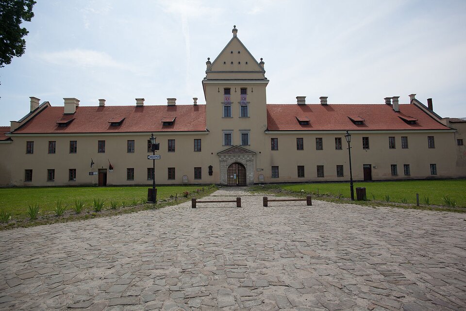 Zdjęcie przedstawia siedemnastowieczny zamek w Żółkwi. Jest to dwuskrzydłowy, jednopiętrowy budynek o spadzistym dachu, w którego części głównej znajduje się wysoka wieża z bramą wjazdową.