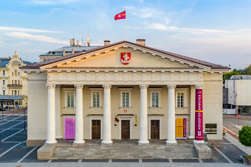 Ilustracja przedstawia budynek Ratusza w Wilnie. Jest piętrowy, z monumentalnym portykiem wspartym na sześciu kolumnach, z trójkątnym tympanonem. Pomiędzy kolumnami a tympanonem znajduje się fryz tryglifowo‑metopowy. Okna na piętrze rozmieszczone są w regularnych odstępach, na parterze, dokładnie pod oknami znajdują się otwory drzwiowe. Bryła budynku jest niewiele szersza od portyku. Dach jest dwuspadzisty, o niewielkim nachyleniu.