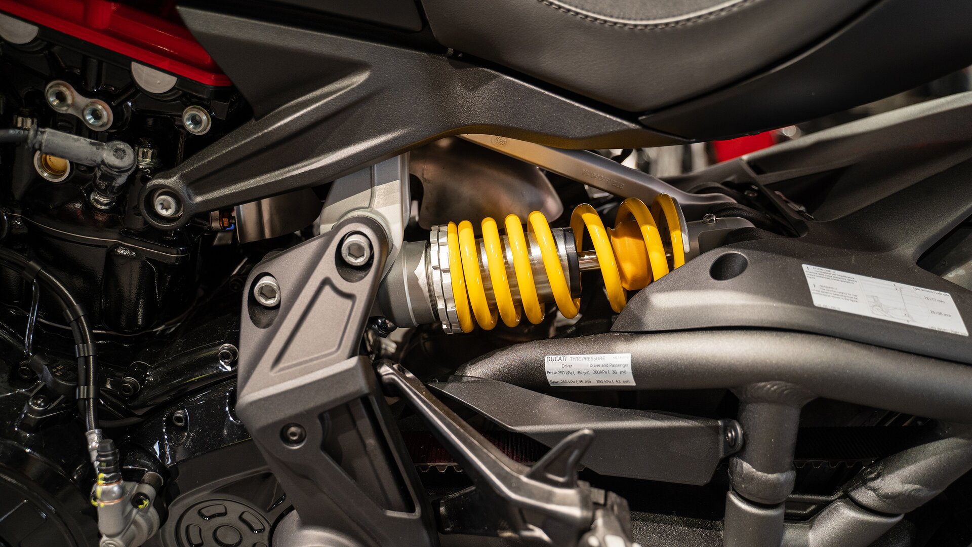 Zdjęcie przedstawia zbliżenie na część motocykla. To poziomo zamocowana żółta szeroka sprężyna. Znajduje się na wale.  