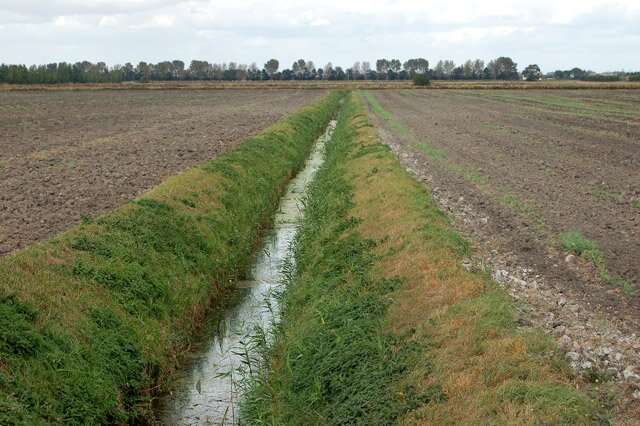 Zdjęcie przedstawia użyźnianie gleby torfem. Widoczne są dwa pola oddzielone rowem.