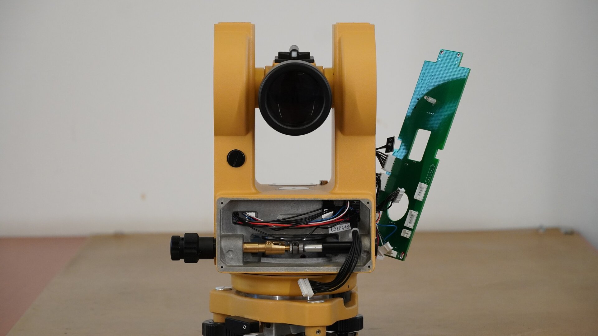 Na zdjęciu ukazano wewnętrzną budowę teodolitu. By to zrobić, zdemontowano boczną osłonę obudowy oraz panel z wyświetlaczem. W miejscu, w którym się znajdował, widoczne są przewody zespołów połączeń wyświetlacza, a także mechanizm leniwki ruchu poziomego wraz z zaciskiem ruchu poziomego. Po prawej stronie widoczna jest płyta główna urządzenia z procesorem.