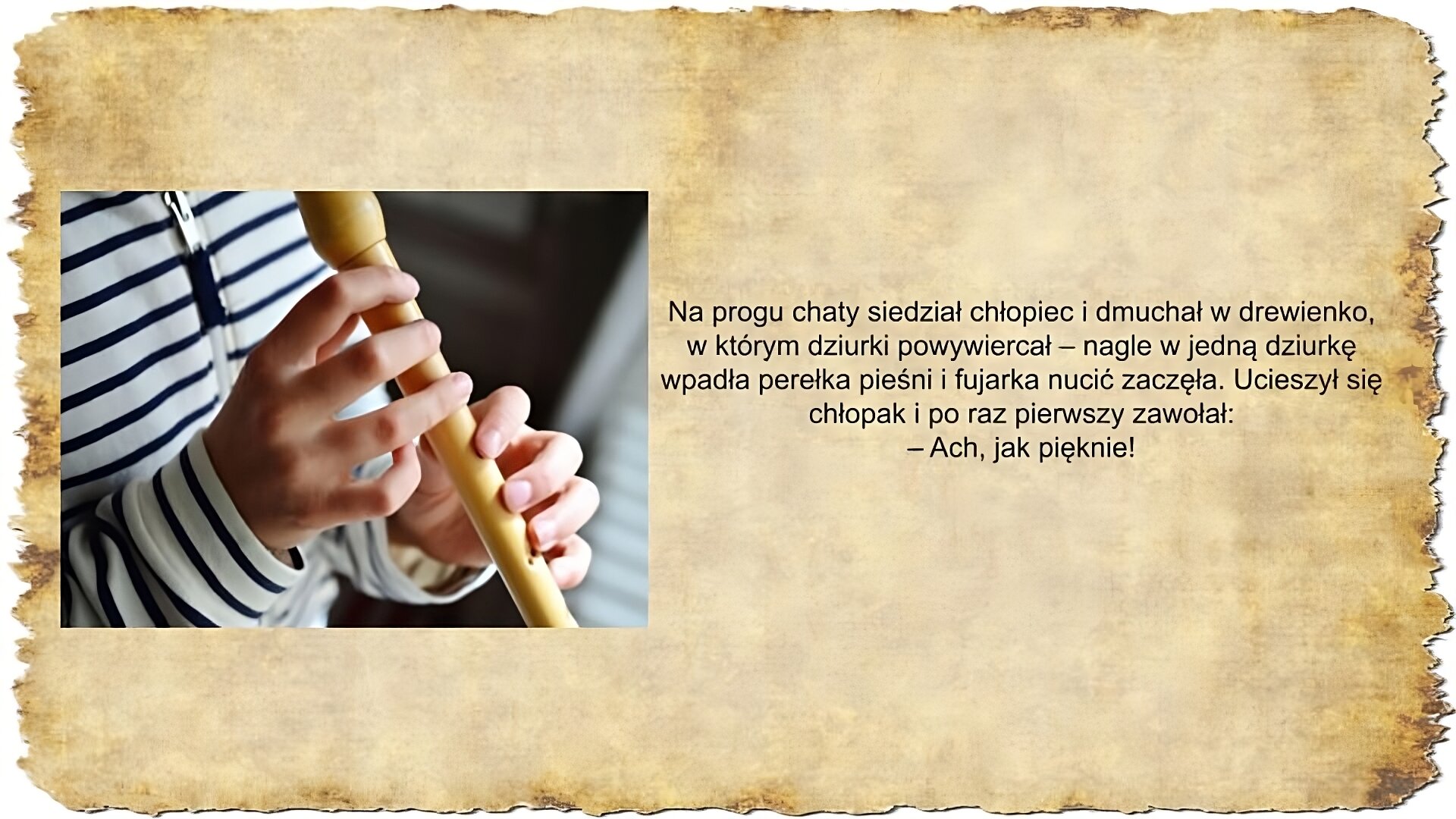 Po prawej stronie slajdu zamieszczony jest tekst: Na progu chaty siedział chłopiec i dmuchał w drewienko, w którym dziurki powywiercał – nagle w jedną dziurkę wpadła perełka pieśni i fujarka nucić zaczęła. Ucieszył się chłopak i po raz pierwszy zawołał: – Ach, jak pięknie! Po lewej stronie slajdu umieszczona jest kolorowa fotografia przedstawiające zbliżenie na drewniany, podłużny instrument z dziurkami po bokach na którym gra dziecko. Nie widać jego twarzy, a jedynie dłonie i granatowo‑białą bluzę w paski, w którą jest ubrany.