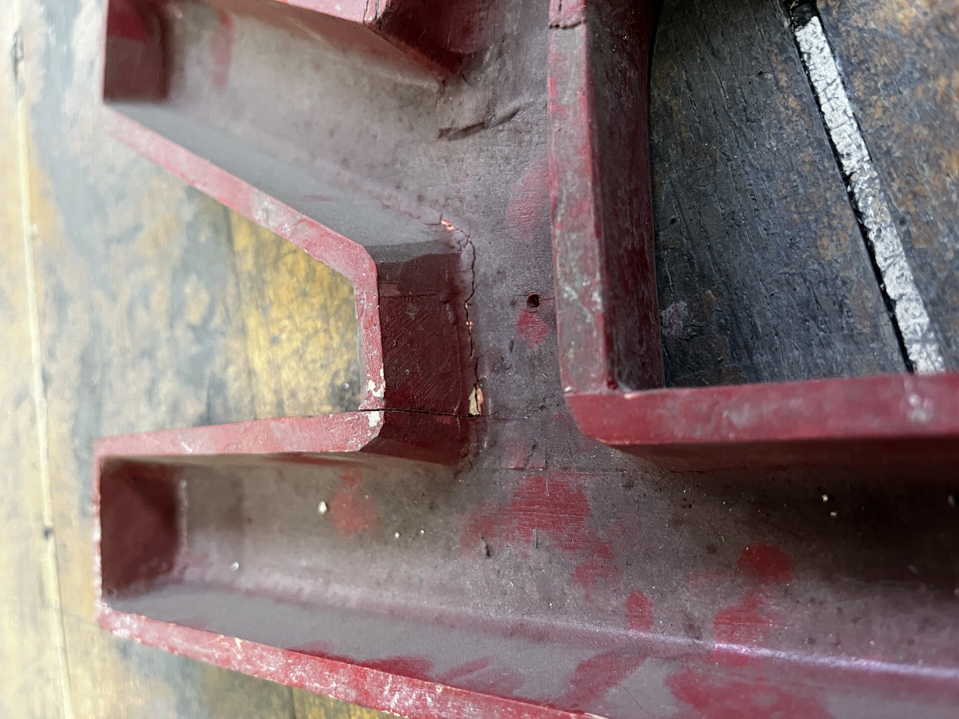 Na zdjęciu pokazano drewniany model odlewniczy z widocznymi pęknięciami. Model jest w kształcie literki: K. Przypomina foremkę. Na ściankach widać pęknięcia przechodzące przez całą grubość ścianki. 