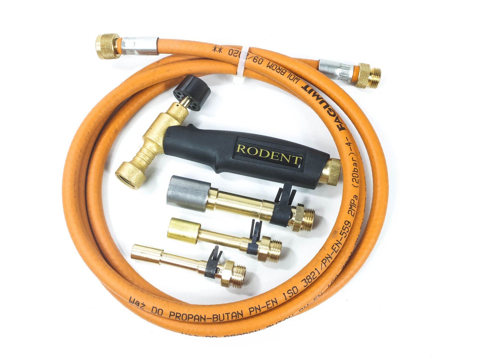 Zdjęcie przedstawia palnik gazowy składający się z rękojeści, dziobu, do którego mocowane są dysze oraz zaworu regulującego dopływ gazu. Obok palnika leżą trzy różnej wielkości dysze. Wokół palnika i dyszy leży zwinięty gumowy wąż do gazu propan‑butan zakończony po dwóch stronach złączkami. Oznaczenie znajdujące się na wężu: PN‑EN ISO 3821/PN‑EN‑559 2MPa (20 bar).