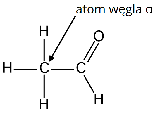 Na ilustracji jest wzór strukturalny: dwa atomy węgla połączone są wiązaniem pojedynczym. Atom węgla - położony po lewej stronie wzoru - został oznaczony literą alfa. Połączony jest wiązaniami pojedynczymi z trzema atomami wodoru, kolejny atom węgla połączony jest wiązaniem podwójnym z atomem tlenu i wiązaniem pojedynczym z atomem wodoru.