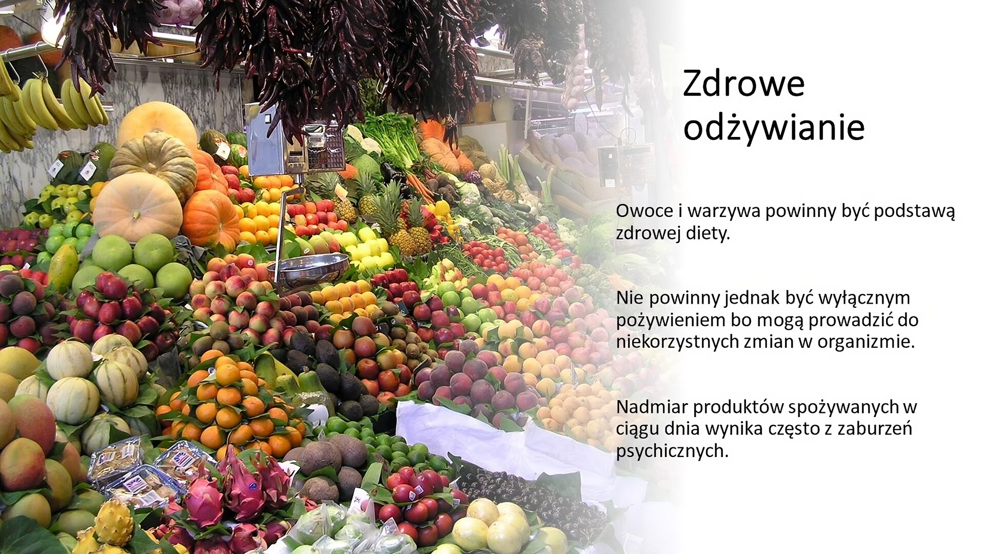 Biały slajd. Z lewej strony zdjęcie targu, na którym zostały ułożone skrzynki z różnymi owocami i warzywami. Z prawej strony slajdu tekst: „Zdrowe odżywianie. Owoce i warzywa powinny być podstawą zdrowej diety. Nie powinny jednak być wyłącznym pożywieniem, bo mogą prowadzić do niekorzystnych zmian w organizmie. Nadmiar produktów spożywanych w ciągu dnia wynika często z zaburzeń psychicznych”.