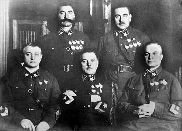 Kliknij, aby powiększyć Zdjęcie przedstawia pięciu mężczyzn, w dwóch rzędach. Ubranych w mundury, do których są przypięte odznaczenia wojskowe. W pierwszym rzędzie od lewej siedzi Michaił Tuchaczewski, Kliment Woroszyłow, Aleksandr Jegorow. W drugim rzędzie od lewej stoi Siemion Budionny, Wasilij Blücher. Zdjęcie wykonane na tle ściany w pomieszczeniu.