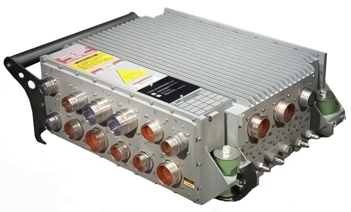 Ilustracja przedstawia komputer fadec. Jest to urządzenie o kształcie graniastosłupa z uchwytem z boku oraz dużą ilością wejść na przewody na dwóch widocznych ściankach bocznych. Na ściance lewej widać dwa rzędy wejść, po sześć wejść w każdym. Wejścia mają różne rozmiary, ale wszystkie są okrągłe. Na prawej ściance widoczne są trzy jednakowe okrągłe wejścia w jednym rzędzie. Na rogach widać również elementy mocowania jednostki.