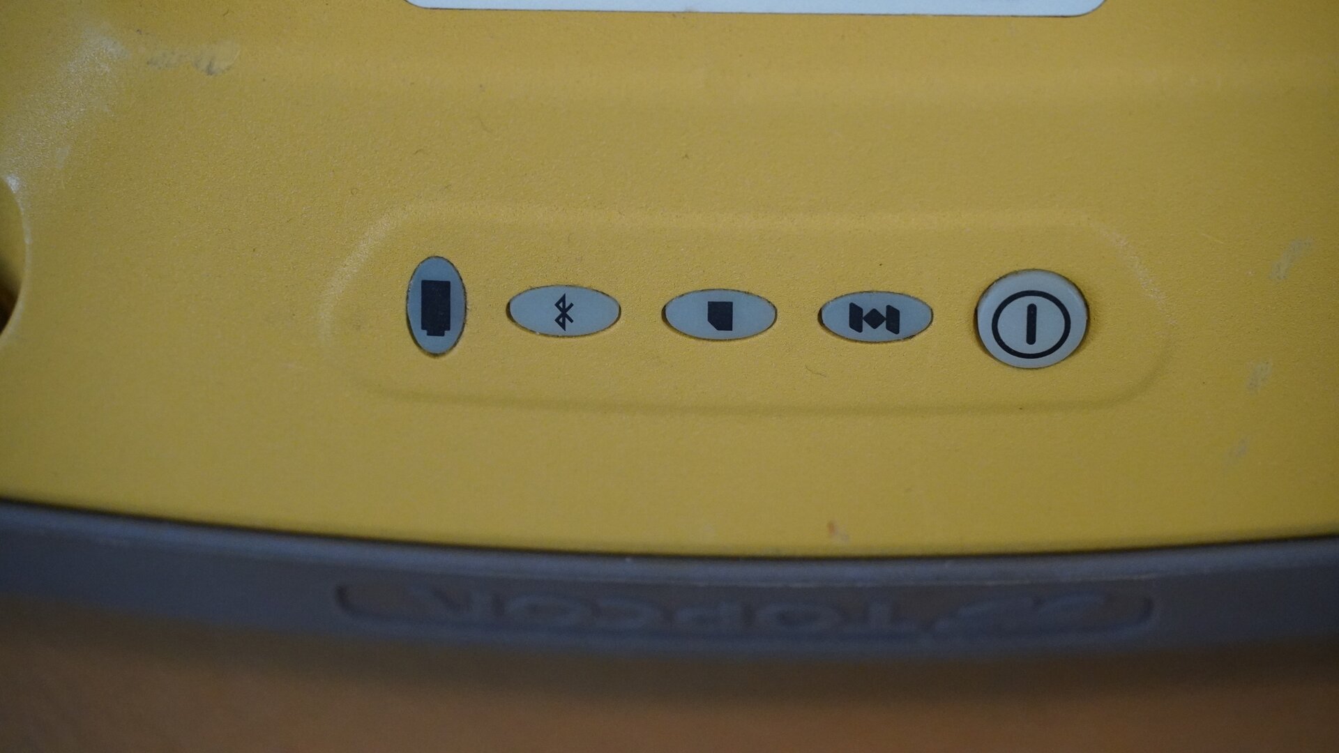 Zdjęcie ukazuje przyciski znajdujące się panelu sterującym urządzenia: włącznik, dioda sygnalizująca status urządzenia, dioda pamięci, dioda bluetooth i wskaźnik baterii. 