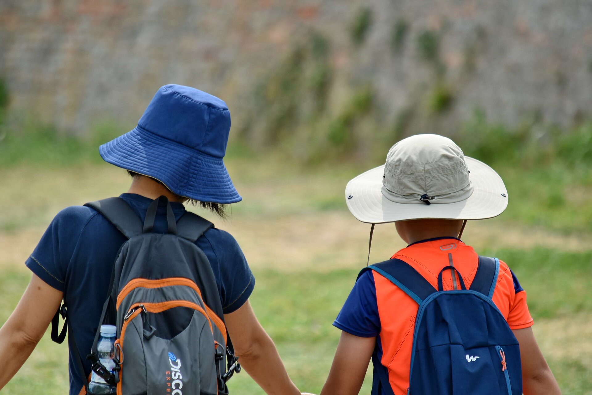 Fotografia przedstawia dwóch chłopców. Na głowach mają czapki a na plecach plecaki. 