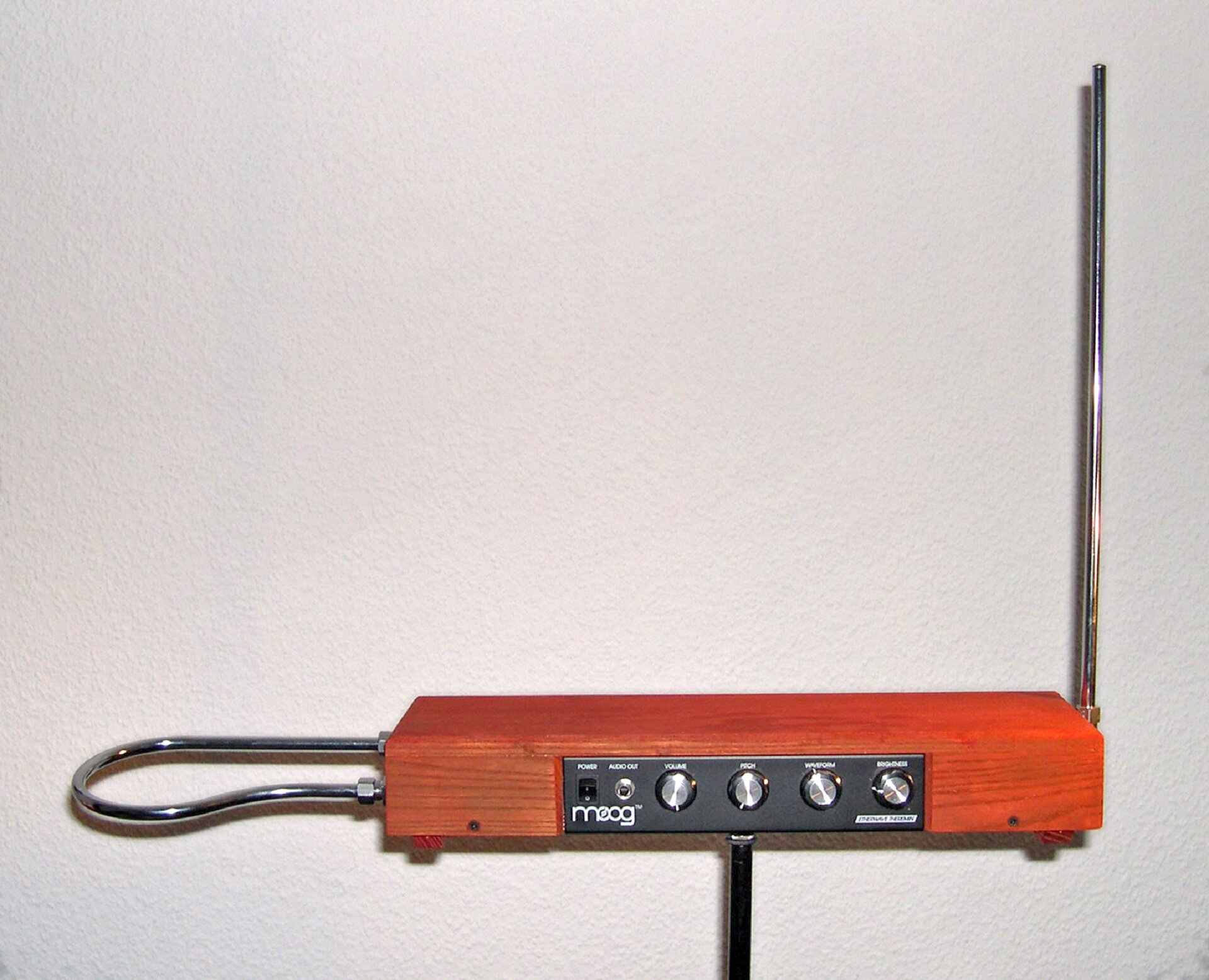 Ilustracja przedstawia theremin - instrument muzyczny z grupy elektrofonów elektronicznych skonstruowany przez rosyjskiego fizyka i wynalazcę Lwa Termena. Dźwięki produkowane przez theremin są ubogie harmonicznie i przypominają w swym brzmieniu wycie, jęk, kobiecy głos, gwizd, piłę, flet, skrzypce lub inne instrumenty. Theremin został wyposażony w dwie anteny – pionową i poziomą. Gra na instrumencie odbywa się poprzez ruch dłońmi w ich obrębie.