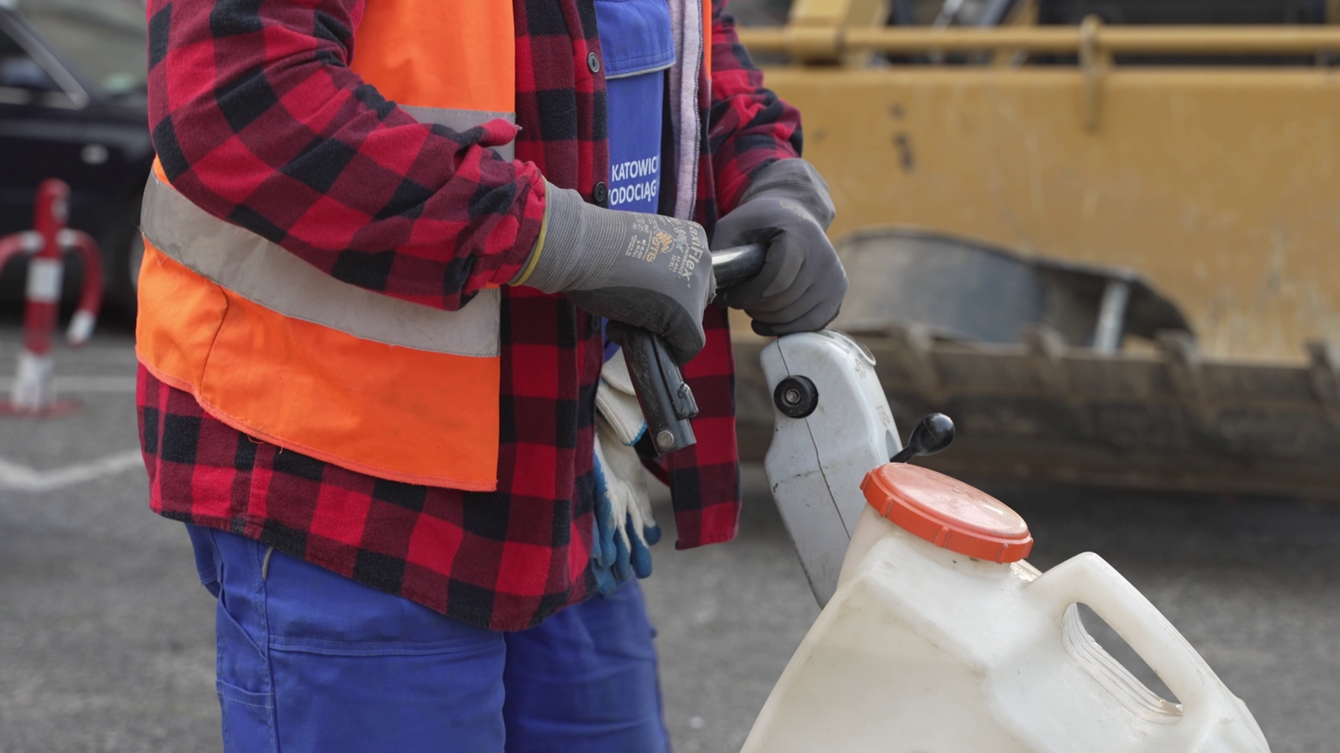 Na grafice przedstawiono rękawice ochronne. Osoba nosząca je pcha maszynę.