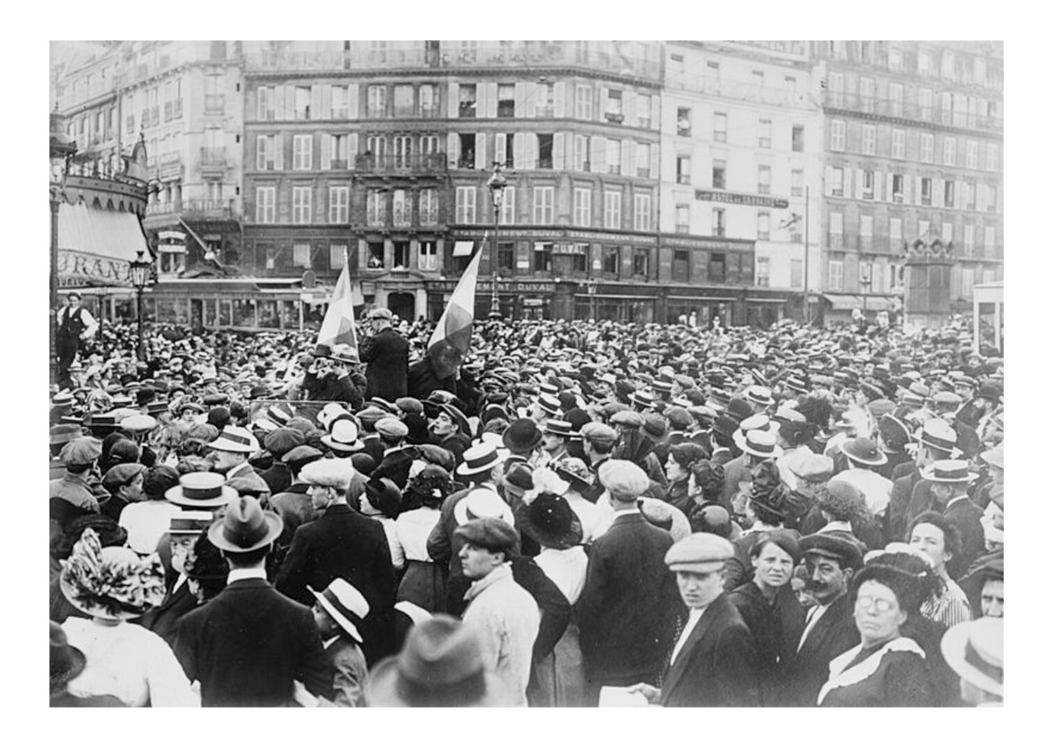 Zdjęcie czarno-białe przedstawiające rezerwistów i tłum ludzi na Gare de l'Est (stacja kolejowa). W tłumie ktoś trzyma flagę.