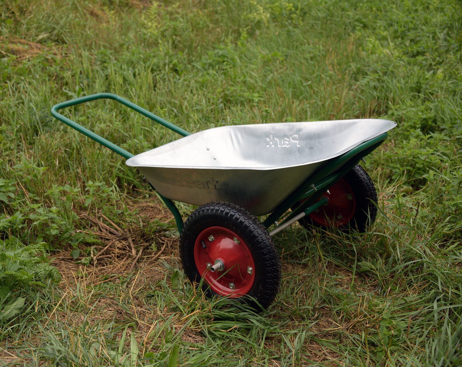 Taczka dwukołowa.Zdjęcie taczki z dwoma kołami. Na konstrukcję wózka składa się pojemnik ładunkowy wykonany z tworzywa sztucznego, dwa koła oraz uchwyt.