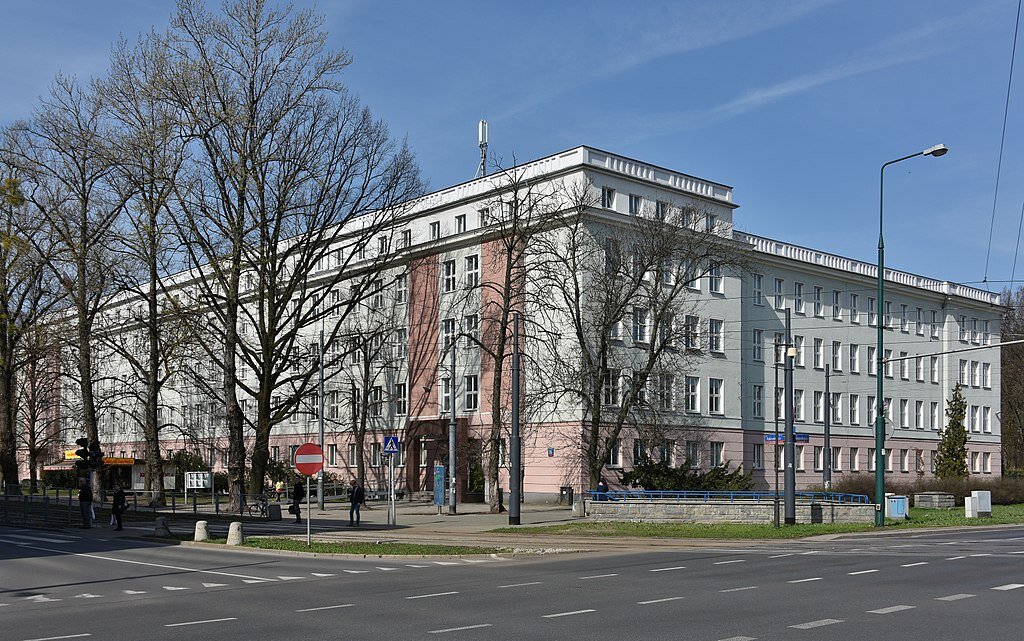 Zdjęcie przedstawia Siedzibę Prokuratury Krajowej w Warszawie. Jest to duży, trzypiętrowy budynek narożny z szerokim wejściem.