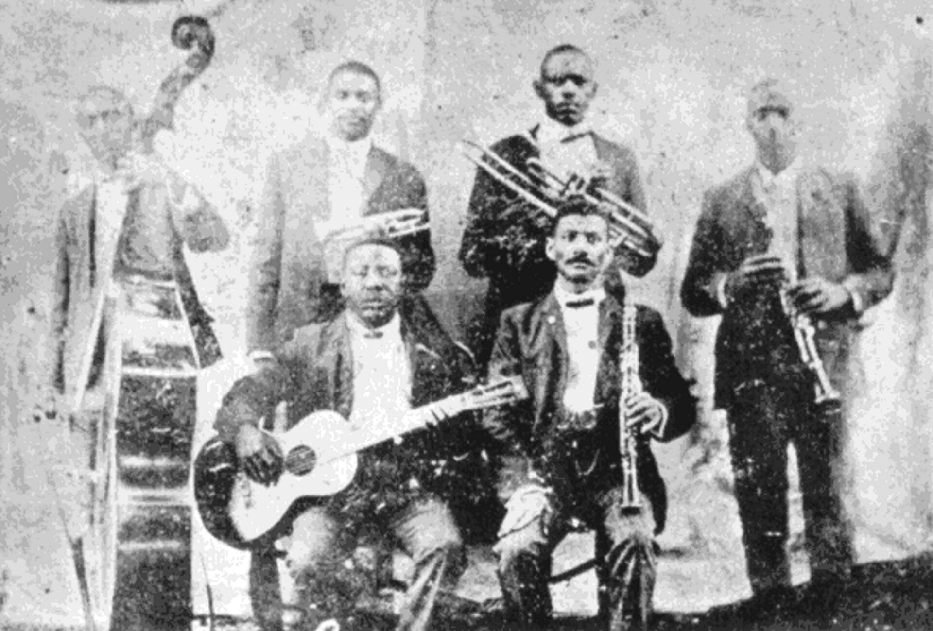 Ilustracja przedstawia sześciu mężczyzn z intrumentami - stoją: Jimmy Johnson (kontrabas), Buddy Bolden (kornet), Willy Cornish (puzon), Willy Warner (klarnet), siedzą: Brock Mumford (gitara), Frank Lewis (klarnet). Mężczyźni ubrani są w ciemne garnitury i białe koszule.
