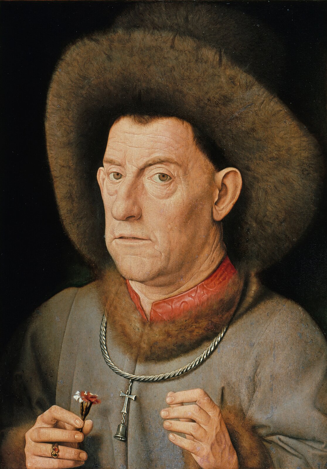 Ilustracja przedstawia obraz Jana van Eycka „Portret mężczyzny z goździkiem”. Ukazuje portret ujęty z lewego półprofilu. Mężczyzna w starszym wieku na na głowie futrzaną czapkę. Również futrem obszyty jest kołnierz płaszcza, spod którego wystaje czerwona stójka. Na szyi mężczyzna ma zawieszony krzyż z dzwoneczkiem, zamocowany na grubym łańcuchu .W ręku trzyma czerwono-biały goździk.