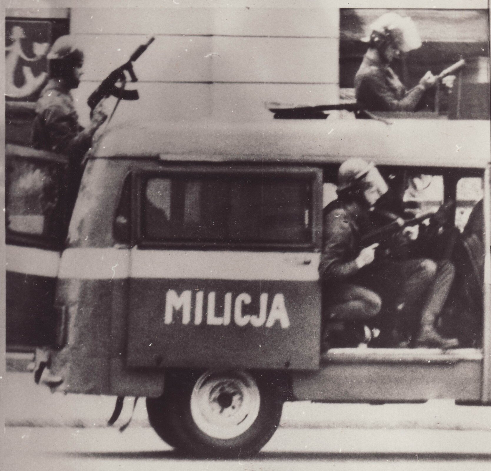 Zdjęcie przedstawia milicyjną Nysę, w której są uzbrojeni w karabiny milicjanci.
