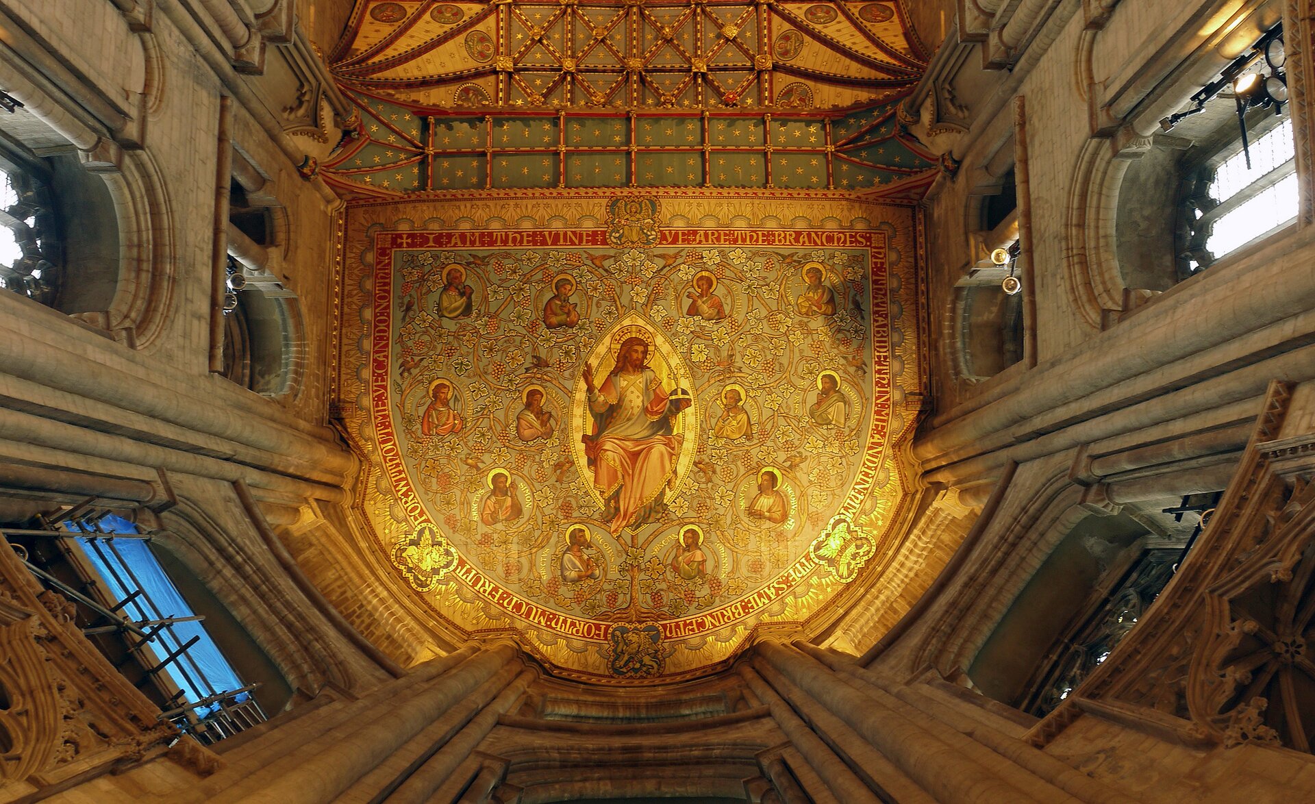 Ilustracja przedstawia sufit Katedry św. Piotra, Pawła i Andrzeja w Peterborough. W centralnej części sufitu, na złotym, wzorzystym tle, namalowany jest Jezus na tle mandorli w kształcie migdała. Otaczają go postacie dwunastu apostołów. Scena zamknięta jest dekoracyjną bordiurą ze złotymi napisami na czerwonym tle. Po bokach znajdują się perspektywicznie ujęte okna, które przedzielają wiązki służek.