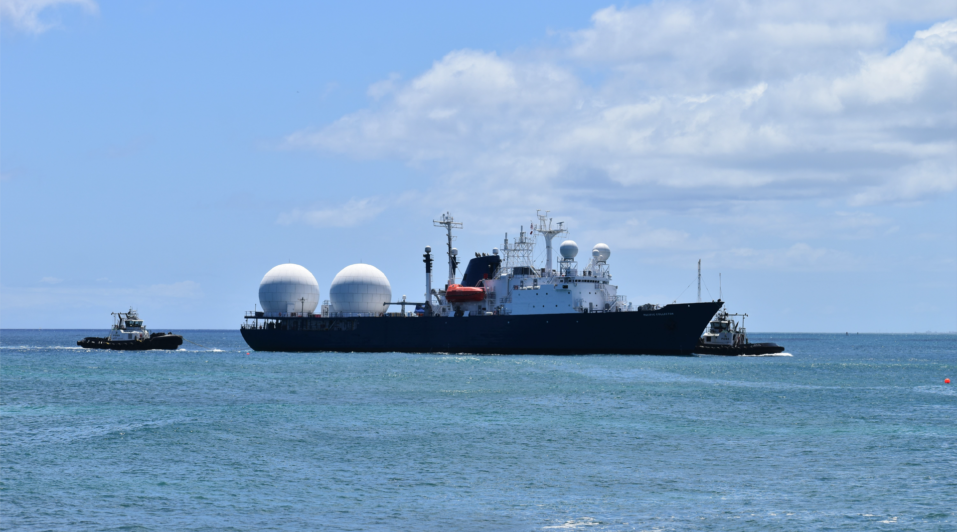 Na zdjęci widoczny jest zbiornikowiec ze zbiornikami sferycznymi. Zbiornikowiec widoczny na zdjęciu ma dwa zbiorniki sferyczne. Mostek statku jest z przodu. Zbiornikowiec płynie po morzu. Za rufą i przed dziobem statku widać mniejszą jednostkę. 