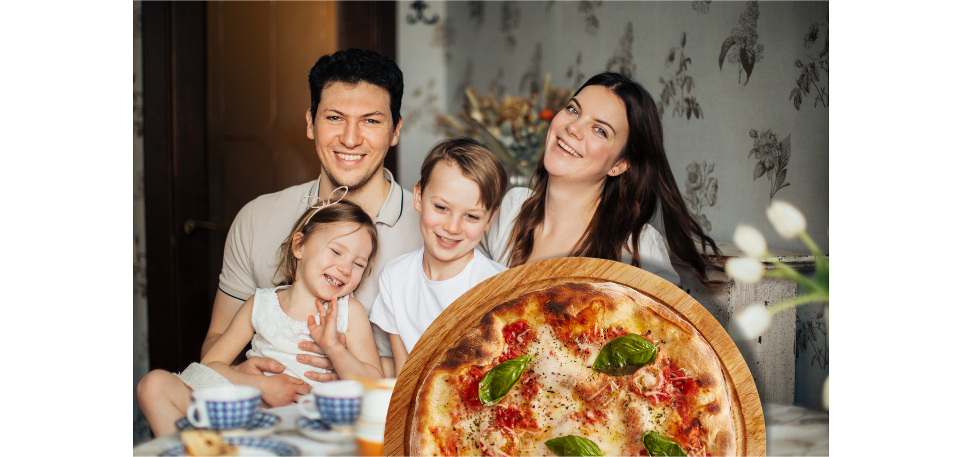 Zdjęcie przedstawia radosną, uśmiechniętą rodzinę, która siedzi przy stole. Po lewej stronie znajduje się mężczyzna, który trzyma na kolanach dziewczynkę. Po prawej stronie siedzi kobieta z długimi włosami. Pomiędzy kobietą a mężczyzną znajduje się chłopiec. Na stole stoją filiżanki. Po prawej stronie na stole znajdują się kwiaty. Na pierwszym planie znajduje się doklejone zdjęcie okrągłej pizzy z serem, pomidorami i listkami bazylii.