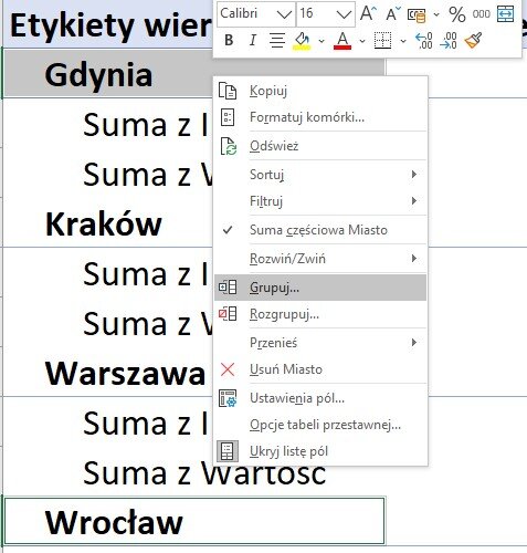 Ilustracja przedstawia fragment arkusza kalkulacyjnego z kolumną A Etykiety wierszy zawierającą nazwy miast (Gdynia, Kraków, Warszawa, Wrocław). Na tle tych danych znajduje się otwarte okno dialogowe z menu kontekstowym i podświetlonym na nim poleceniem Grupuj.