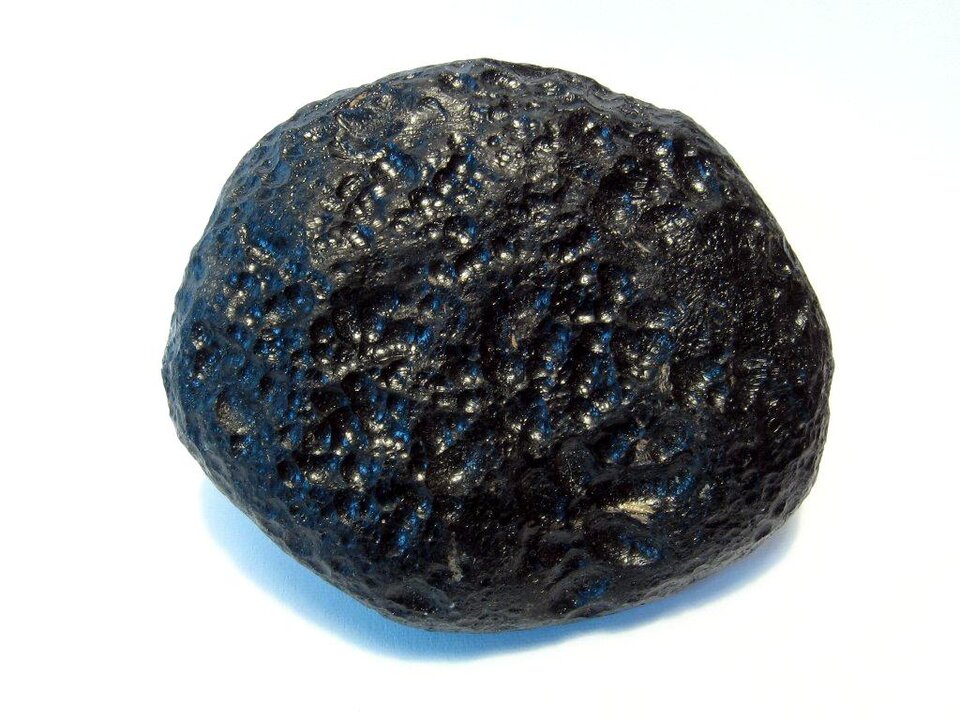 Na zdjęciu znajduje się okrągły kamień o chropowatej, ale połyskliwej powierzchni. Ma czarny kolor.