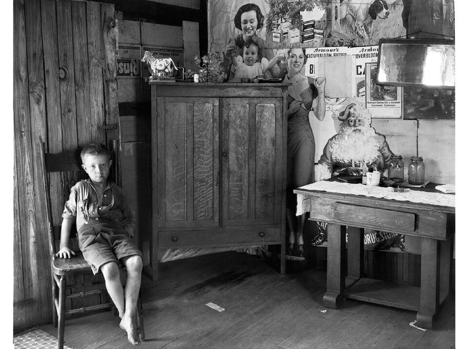 Ilustracja przedstawia fotografię Walkera Evansa pt. „West Virginia Living Room” z 1935 roku, która ukazuje chłopca siedzącego na krześle, wewnątrz pomieszczenia, którego jedna ze ścian wyklejona jest plakatami o różnej tematyce. Chłopiec ubrany jest w koszulę z podwiniętymi rękawami i krótkie spodenki. W rogu stoi drewniana komoda przy niej stół. Na komodzie znajduje się kilka przedmiotów dekoracyjnych, m.in. figurka krowy, aluminiowa gałązka, małe pudełeczka. Na stole, przykrytym bieżnikiem, stoją dwa słoiki, kubek oraz leży zeszyt.